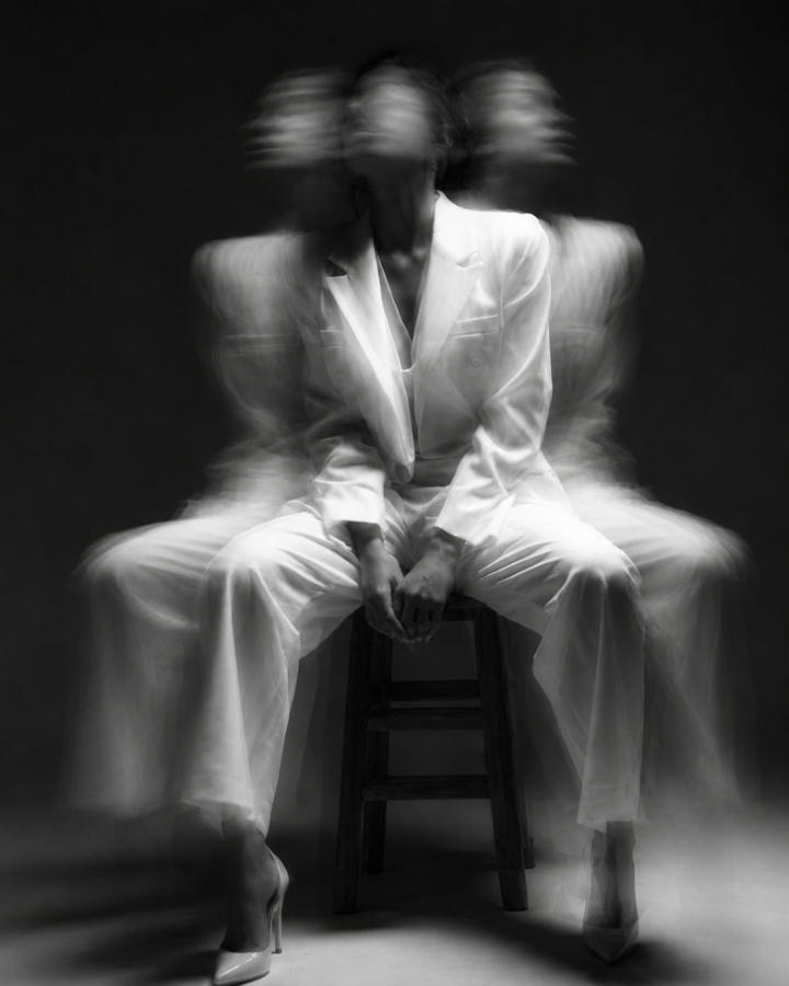 Mulher de terno branco sentada em um banco, em fotografia com efeito de movimento